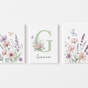 May include: Three framed floral art prints. Each print features watercolor flowers in pink, purple, and white, with butterflies. The center print has a large green letter "G" and the name "Gianna".