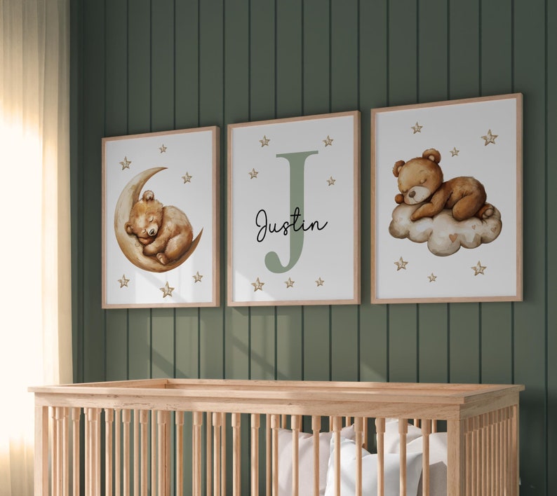 May include: Three framed prints with a green background. The prints feature a sleeping bear on a crescent moon, a large letter J with the name Justin, and a sleeping bear on a cloud. Each print has a white background with gold stars.