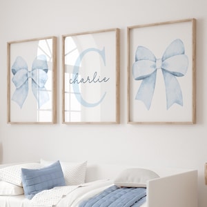 May include: Three framed prints with a light blue watercolor bow design. The middle print features the letter "C" and the name "charlie" in a light blue script font.