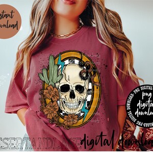 May include: A digital download design featuring a skull with a snake wrapped around it, surrounded by desert plants and flowers. The design is in a yellow circle with a checkered background. The text "digital downloads" is at the bottom of the image.
