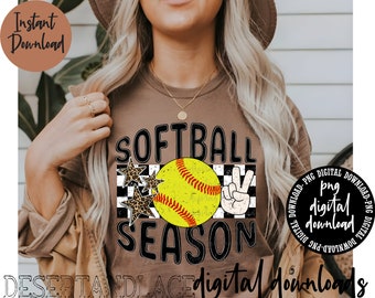 Könnte beinhalten: Ein braunes T-Shirt mit dem Text "SOFTBALL SEASON" in Schwarz. Das Design beinhaltet einen gelben Softball mit roten Nähten, zwei schwarze Sterne mit weißen Umrissen und ein Peace-Zeichen mit einem schwarz-weiß karierten Hintergrund.