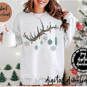 May include: A white sweatshirt with a brown antler design and colorful ornaments hanging from it. The antler design has lights on it. The sweatshirt is a digital download.