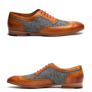 May include: Tan leather brogue shoes with a gray and black herringbone pattern on the toe and side panels. The shoes have red laces.