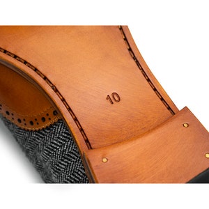 May include: Close-up of the sole of a brown leather shoe with a gray tweed upper. The shoe size, "10", is embossed on the sole.