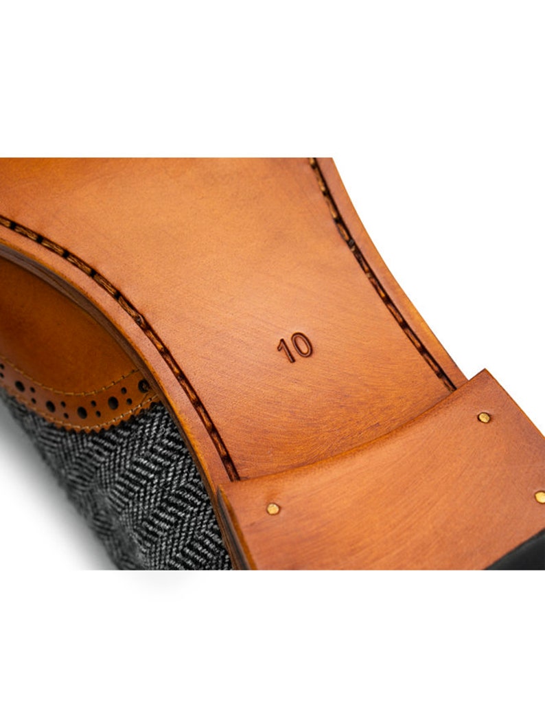 May include: Close-up of the sole of a brown leather shoe with a gray tweed upper. The shoe size, "10", is embossed on the sole.