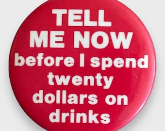 May include: A circular, red button with white lettering. The text says "TELL ME NOW before I spend twenty dollars on drinks."