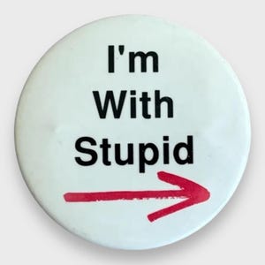 Può includere: Un bottone rotondo bianco con la scritta "I'm With Stupid" in nero e una freccia rossa che punta a destra. Un accessorio umoristico e audace.