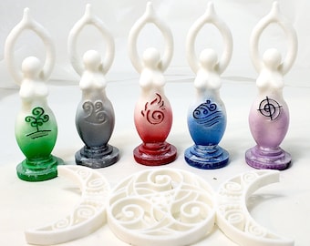 May include: A collection of five white goddess figurines, each with a different colored base and symbol representing earth, air, fire, water, and spirit. A white crescent moon and circle design is in the foreground.