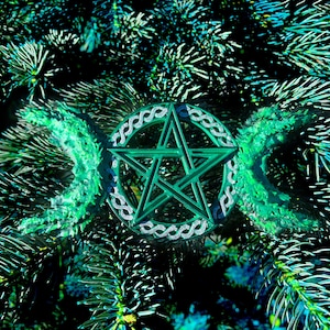 May include: A green pentagram with a triple moon symbol, surrounded by a Celtic knot design, is set against a background of green pine needles.