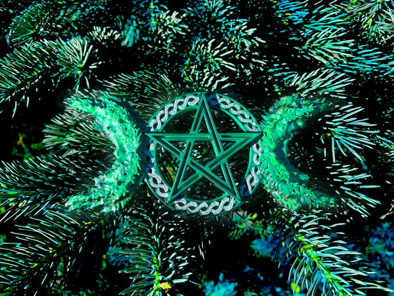 May include: A green pentagram with a triple moon symbol, surrounded by a Celtic knot design, is set against a background of green pine needles.