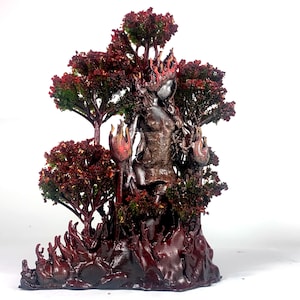 May include: A dark red and brown sculpture of a woman standing in a forest of trees. The woman is surrounded by flames and the trees are made of a textured material.