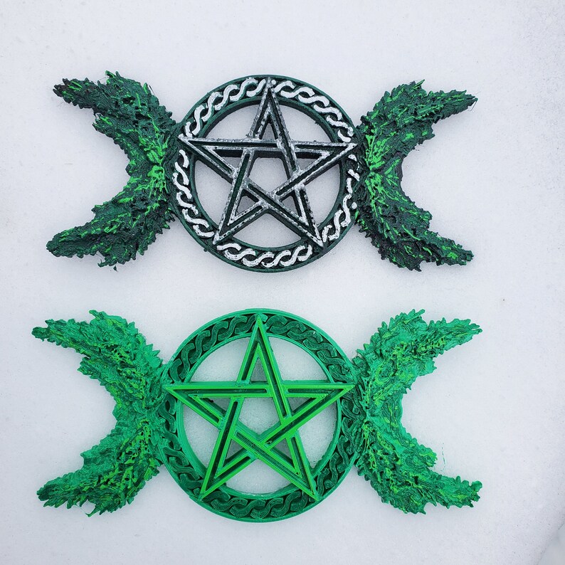 May include: Two triple moon pentagram wall decor pieces. One is silver with a green background and the other is green with a green background.