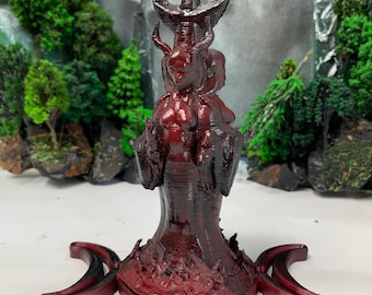 May include: A 3D printed red and black statue of a female figure with horns and a crown. The figure is standing on a base with a triple moon symbol.