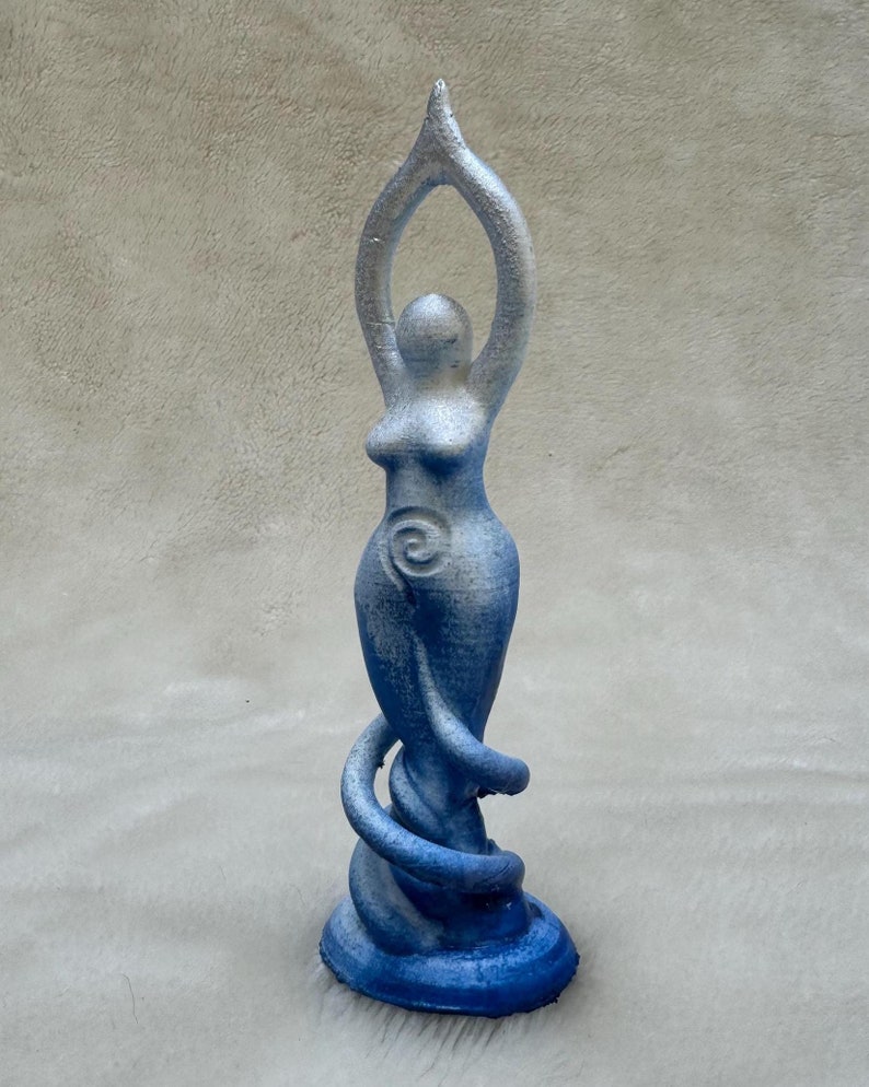 May include: A blue and white ceramic statue of a woman with her arms raised above her head. The statue is standing on a base with a spiral design.