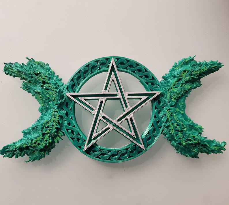 May include: A green and silver pentagram with a triple moon symbol on either side. The pentagram is surrounded by a circle with a Celtic knot design.