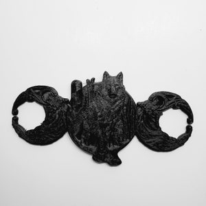 May include: Black and white 3D printed wall decor featuring a wolf inside a triple moon symbol.