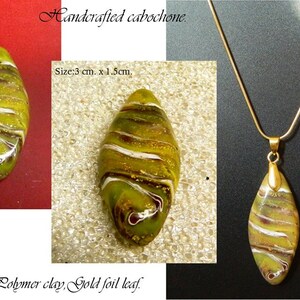 May include: A handcrafted green and gold cabochon pendant with white swirls. The pendant is 3 inches long and 1.5 inches wide. It is made of polymer clay and gold foil leaf. The pendant is hanging from a gold chain.