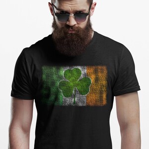 May include: A black t-shirt with a distressed Irish flag design featuring a green shamrock.