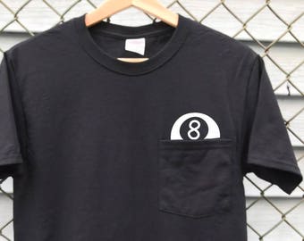 May include: Black t-shirt with a pocket featuring a white 8-ball graphic.