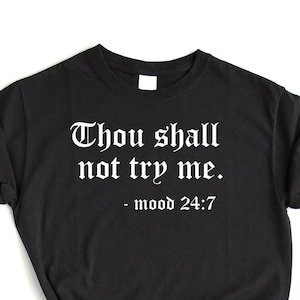 May include: Black t-shirt with white text that reads "Thou shall not try me. - mood 24:7"