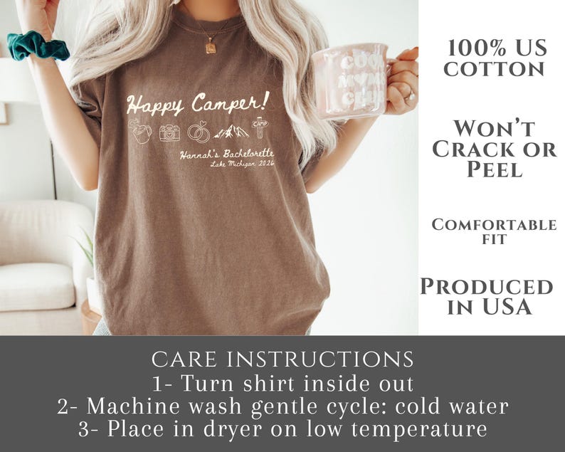 Puede incluir: Camiseta marr&oacute;n con el texto "Happy Camper!" e iconos de camping. El texto "Hannah's Bachelorette Lake Michigan 2026" est&aacute; debajo. Hecha de 100% algod&oacute;n estadounidense y producida en EE. UU. Tambi&eacute;n se incluyen instrucciones de cuidado.