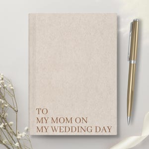 May include: A beige journal with the text "TO MY MOM ON MY WEDDING DAY" printed in brown on the front cover.