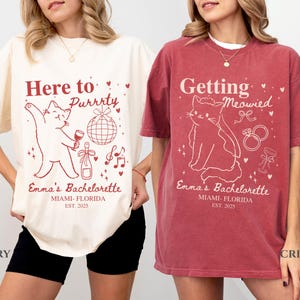 Puede incluir: Dos camisetas, una marfil y otra carmes&iacute;, con dise&ntilde;os a juego con tem&aacute;tica de gatos para una despedida de soltera. La camiseta marfil dice "Here to Purrrty" y la camiseta carmes&iacute; dice "Getting Meowied". Ambas camisetas incluyen "Emma's Bachelorette, Miami-Florida, EST. 2025".