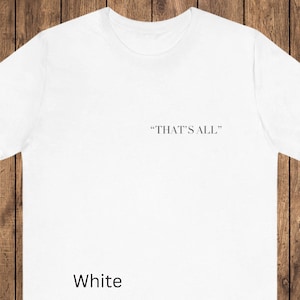 May include: White t-shirt with the text "THAT'S ALL" printed in black near the neckline. The word "White" is printed in a bold font at the bottom of the shirt.