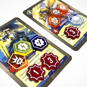 May include: Two game cards with hexagonal dice on top. The card on the left shows a knight with a sword and the text "Staunch Knight gets +2 power while it is on the play". The card on the right shows a creature with wings and the text "Raiding King. Play from this card. When this card returns to your hand".