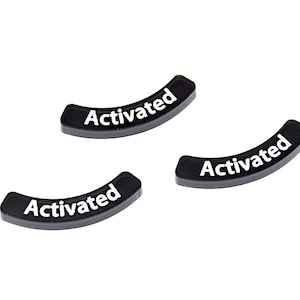Könnte beinhalten: Drei schwarze, gebogene Kunststoffteile mit dem Wort "Activated" in Weiß aufgedruckt. Die Teile sind auf weißem Hintergrund angeordnet. Der Text ist in einer serifenlosen Schriftart.