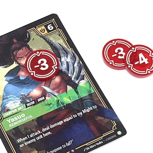 May include: A game card featuring a character illustration and text, with two red tokens displaying negative numbers. The card has a black border and gold accents. The tokens are red with white numerals.