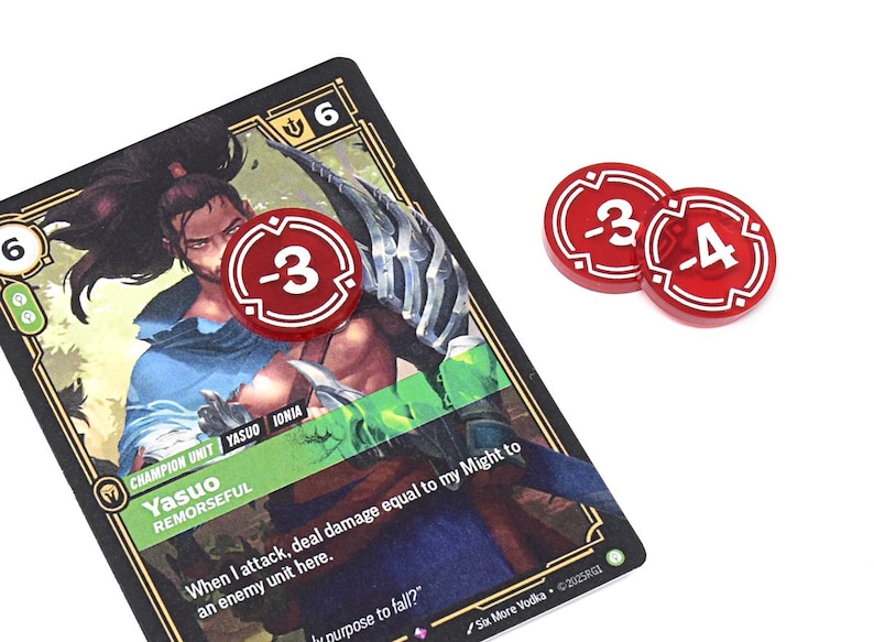 May include: A game card featuring a character illustration and text, with two red tokens displaying negative numbers. The card has a black border and gold accents. The tokens are red with white numerals.
