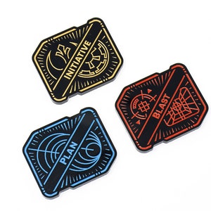 May include: Three black and white enamel pins with different colored accents. The pins feature a stylized design with the words "PLAN", "BLAST", and "INITIATIVE" written across them.