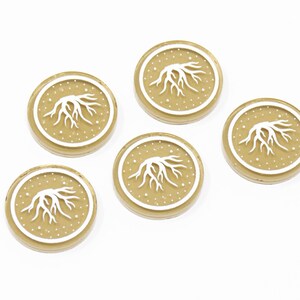 May include: Five gold-colored tokens with a white tree root design and white dots on a white background.