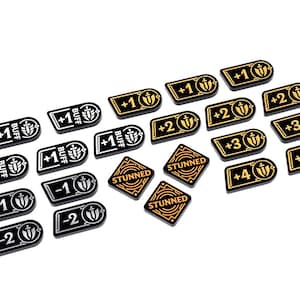 May include: A collection of black and gold game tokens with various markings. Some tokens have "+1 BUFF" and "+2" to "+4" symbols. Other tokens read "STUNNED" or "-1" and "-2". The tokens are likely used in a tabletop game.