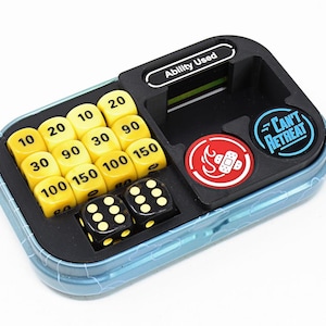May include: A blue and black game organizer with yellow dice displaying numbers from 10 to 150. Two black dice are also included. The organizer has the text "Ability Used" and two circular tokens with text and graphics.