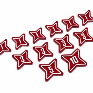 May include: A set of ten red star-shaped dice with white numbers. The numbers are 1, 3, 5, and 10.
