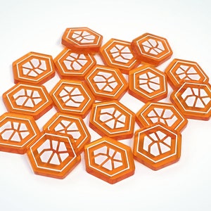 May include: A group of 16 orange hexagonal game tokens with a white honeycomb design.