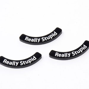 Könnte beinhalten: Drei schwarze, gebogene Plastikstücke mit dem Text "Really Stupid" in weiß.