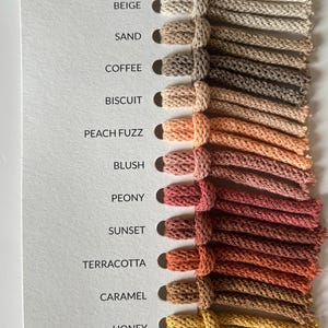 Pu&ograve; includere: Scheda colori con una gamma di colori di filato, dai neutri chiari ai gialli vibranti. La scheda mostra nomi come "Natural", "Beige", "Senape" e "Giallo Piccante". Ogni colore &egrave; rappresentato da un campione di filato annodato.