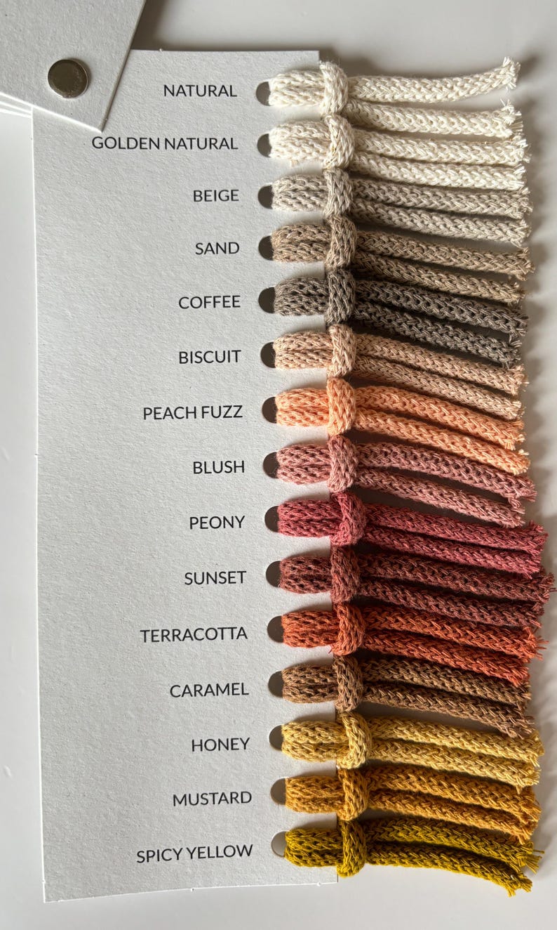 Pu&ograve; includere: Scheda colori con una gamma di colori di filato, dai neutri chiari ai gialli vibranti. La scheda mostra nomi come "Natural", "Beige", "Senape" e "Giallo Piccante". Ogni colore &egrave; rappresentato da un campione di filato annodato.