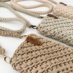 Peut inclure: Gros plan sur plusieurs &eacute;tuis de t&eacute;l&eacute;phone en macram&eacute; beige avec des lani&egrave;res assorties. Les &eacute;tuis pr&eacute;sentent un motif tiss&eacute; textur&eacute; et sont orn&eacute;s de petites &eacute;tiquettes en cuir marron. Les lani&egrave;res et les &eacute;tuis sont dans des tons beiges vari&eacute;s.