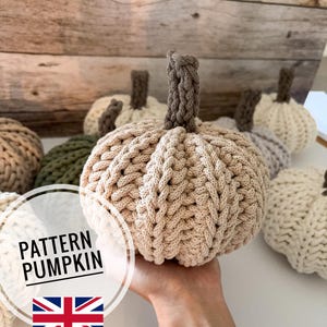 Puede incluir: Una colección de calabazas tejidas a mano, en varios colores neutros. Las calabazas tienen cuerpos texturizados y tejidos y tallos marrones. La imagen incluye una calabaza sostenida en una mano y un gráfico que dice "PATTERN PUMPKIN" con una bandera británica.