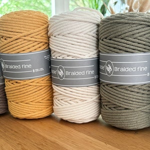 May include: Six spools of cotton cord in various colors, including natural, gray, yellow, green, and blue. The spools are labeled with the text "Braided Fine" and "Durable".