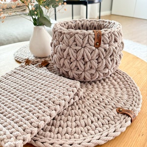 Può includere: Un set di tre sottobicchieri in crochet beige e un cestino in crochet beige con un'etichetta in pelle marrone che dice "Handmade with Love".