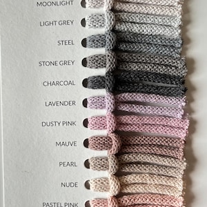 Pu&ograve; includere: Scheda colori con campioni di cordoncini intrecciati in varie tonalit&agrave;. I colori includono bianco, grigio, rosa e bordeaux. Ogni campione &egrave; etichettato con il suo nome di colore.