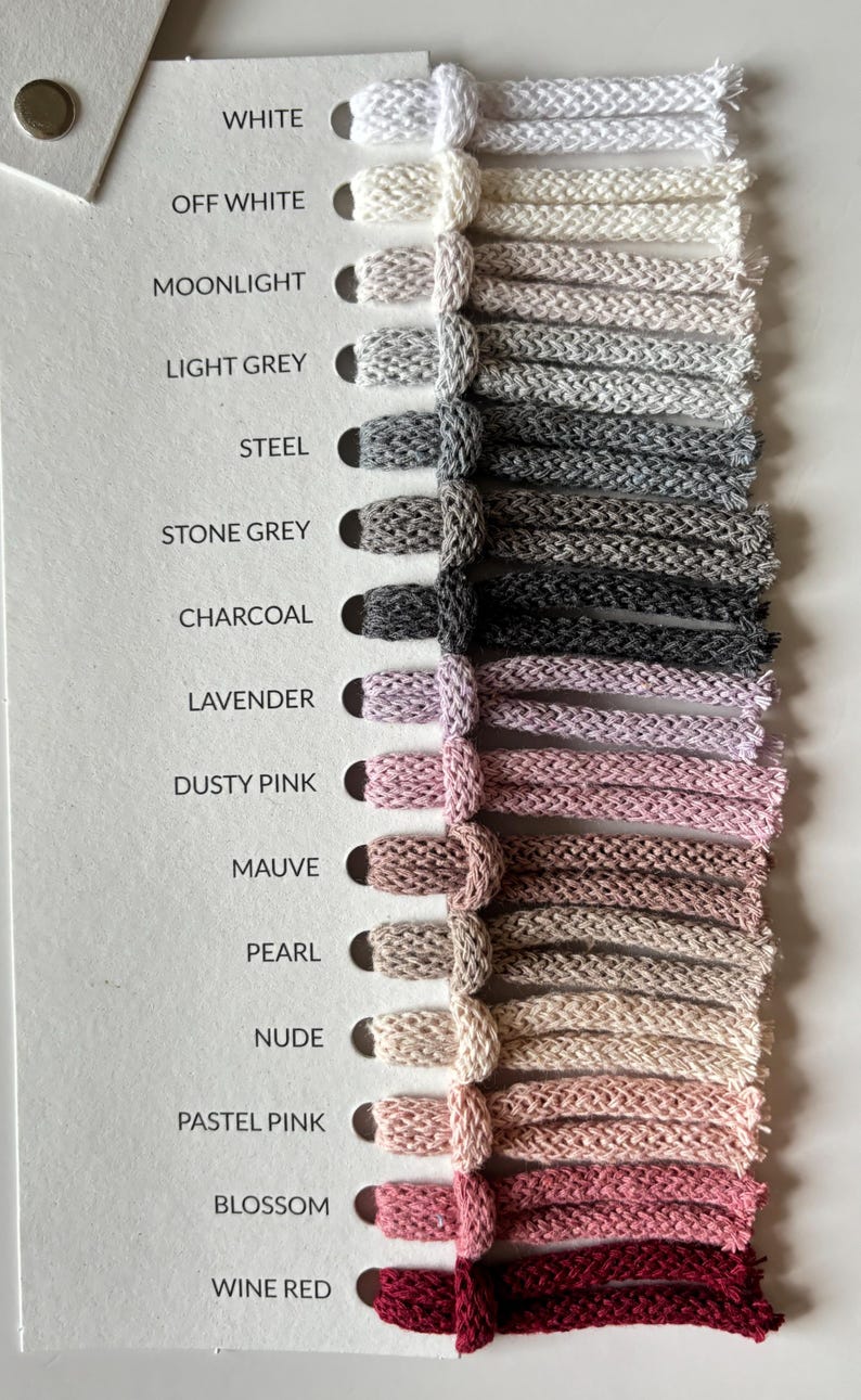 Pu&ograve; includere: Scheda colori con campioni di cordoncini intrecciati in varie tonalit&agrave;. I colori includono bianco, grigio, rosa e bordeaux. Ogni campione &egrave; etichettato con il suo nome di colore.