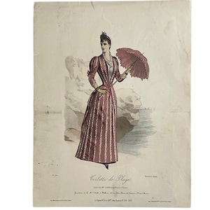 Può includere: Un'illustrazione vintage di una donna che indossa un abito a righe rosa e bianche con un bordo in pizzo bianco. Tiene un ombrello rosso e si trova su una spiaggia rocciosa. Il testo "Toilette de Plage" è stampato sotto l'immagine.