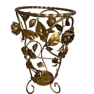 Peut inclure: Un vase décoratif en métal doré avec un motif floral. Le vase présente des roses et des feuilles, avec un bord torsadé en forme de corde. Le vase a trois pieds incurvés et convient à la décoration intérieure.