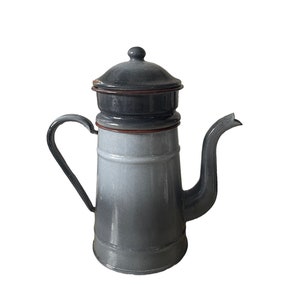 May include: A gray enamel coffee pot with a brown rim and a lid. The pot has a spout and a handle.